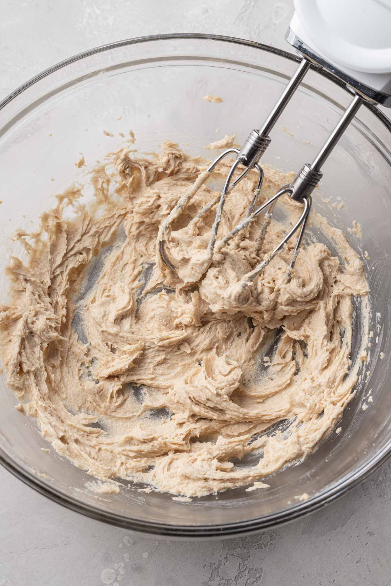 An overhead view of creamed butter and sugar in a glass mixing bowl. 