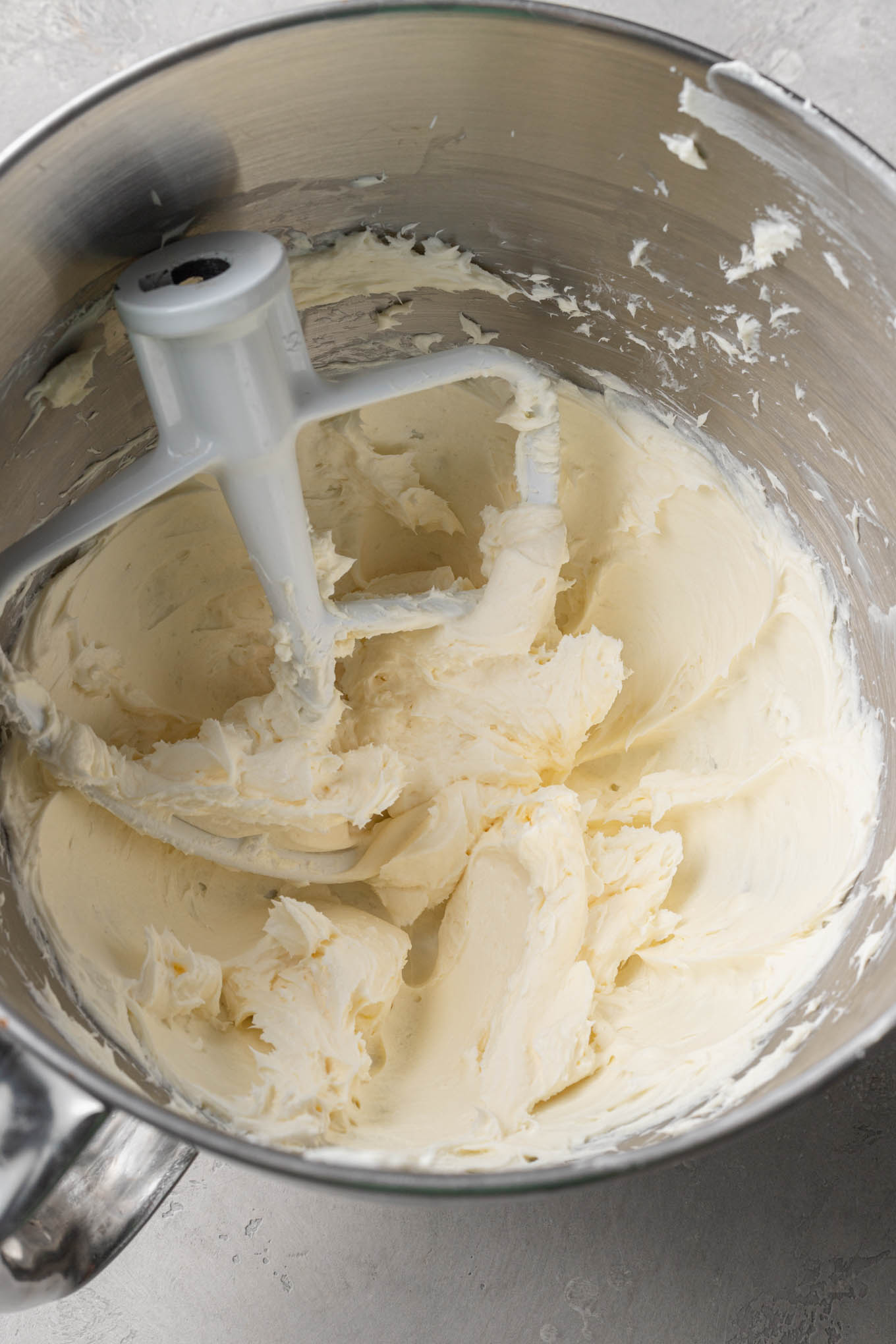 An overhead view of cream cheese and butter in the bowl of a stand mixer. 