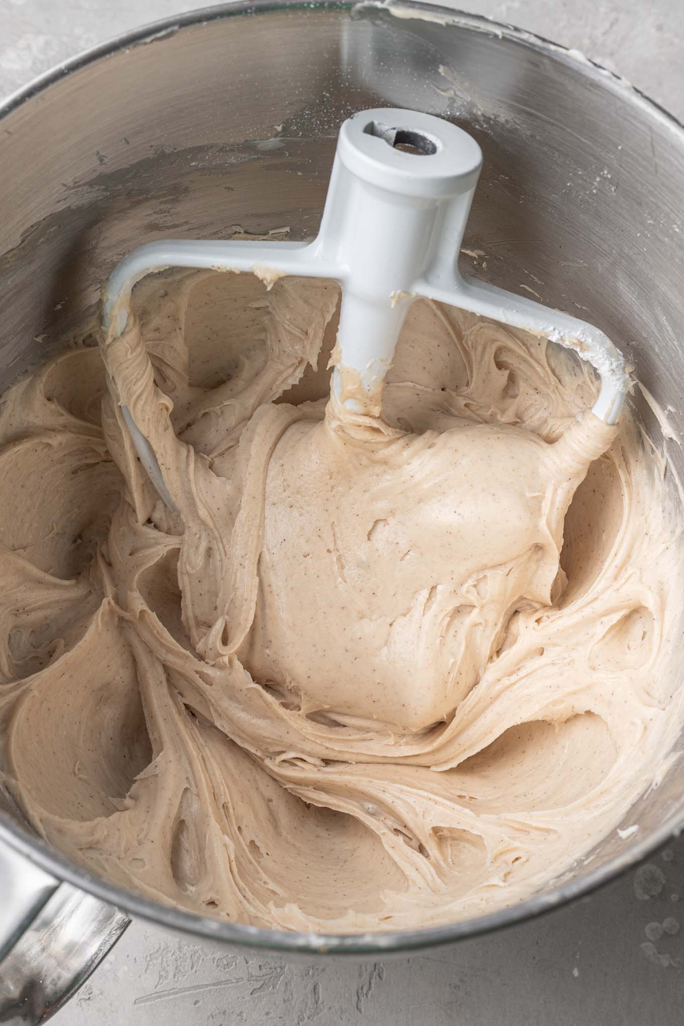 An overhead view of brown sugar cinnamon cream cheese frosting in the bowl of a stand mixer. 