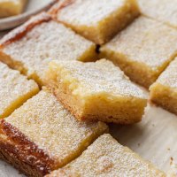 Several sliced gooey butter bars on a piece of brown parchment paper.