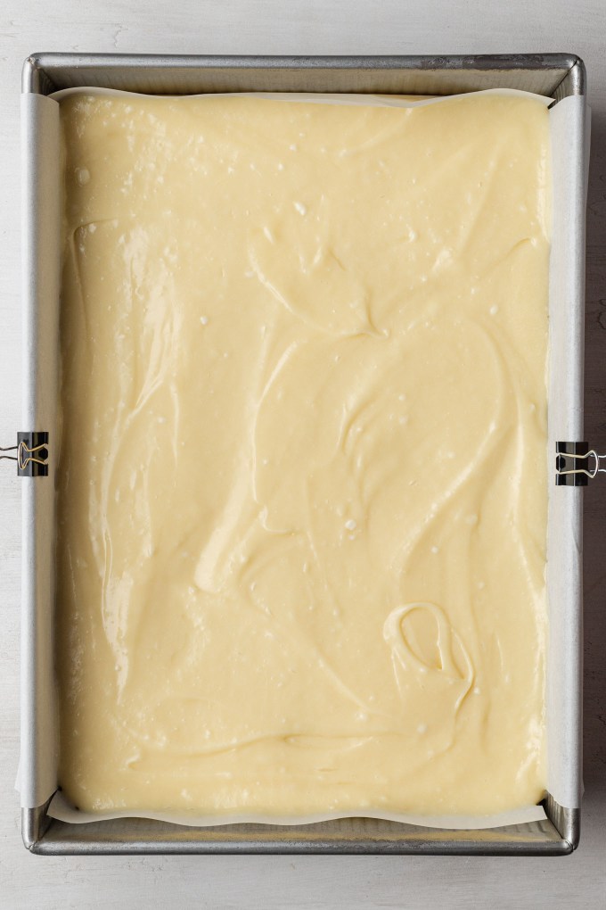 An overhead view of an unbaked gooey butter cake in a baking pan.