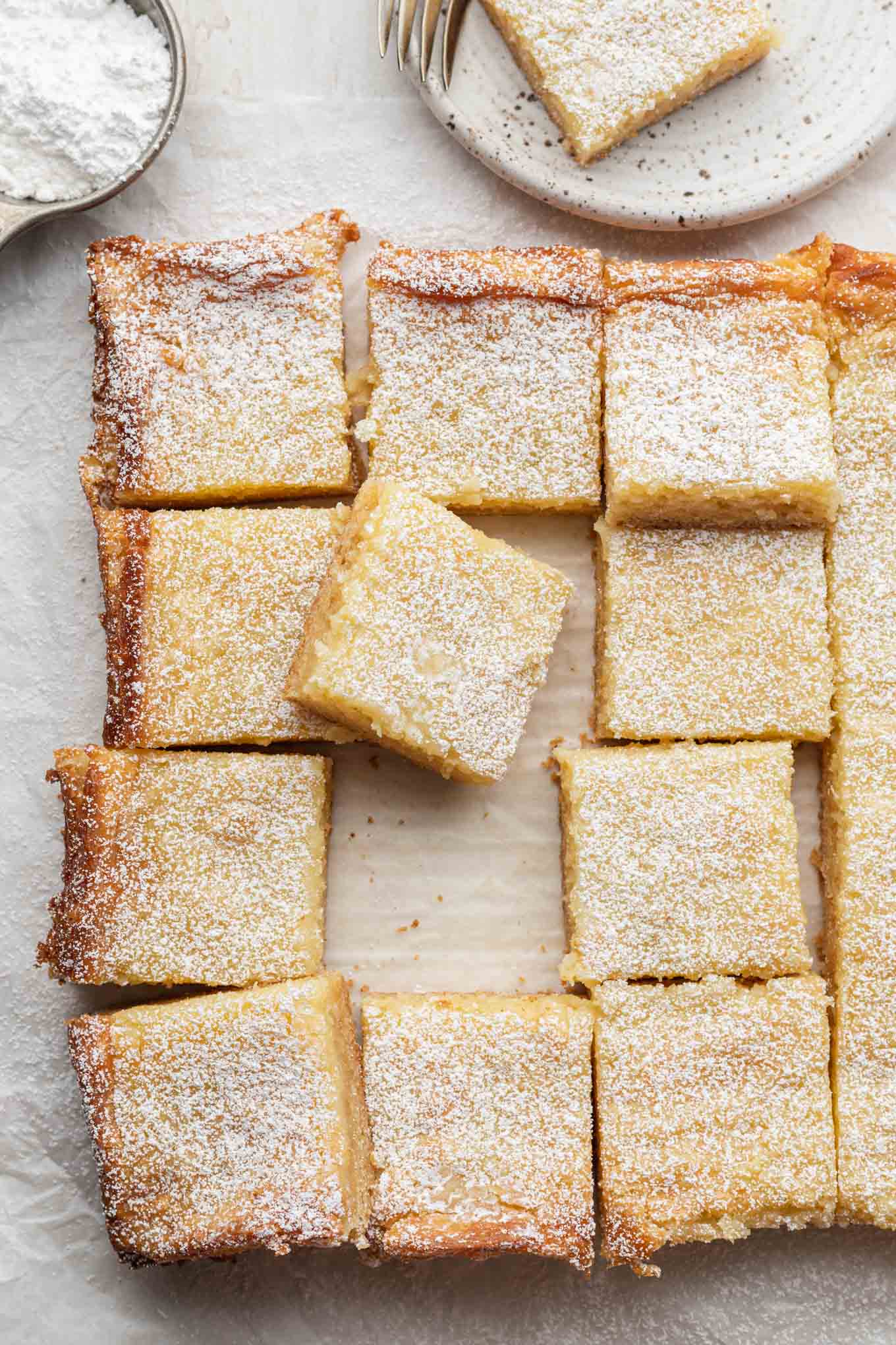 An overhead view of a sliced gooey butter cake, with one slice resting on another. 