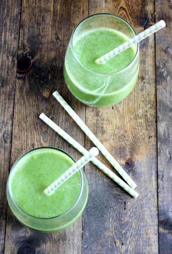 Overhead view of two spinach banana smoothies with straws. 