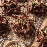 Several haystack cookies topped with red and green sprinkles on a small wire rack.