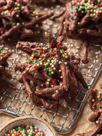 Several haystack cookies topped with red and green sprinkles on a small wire rack.