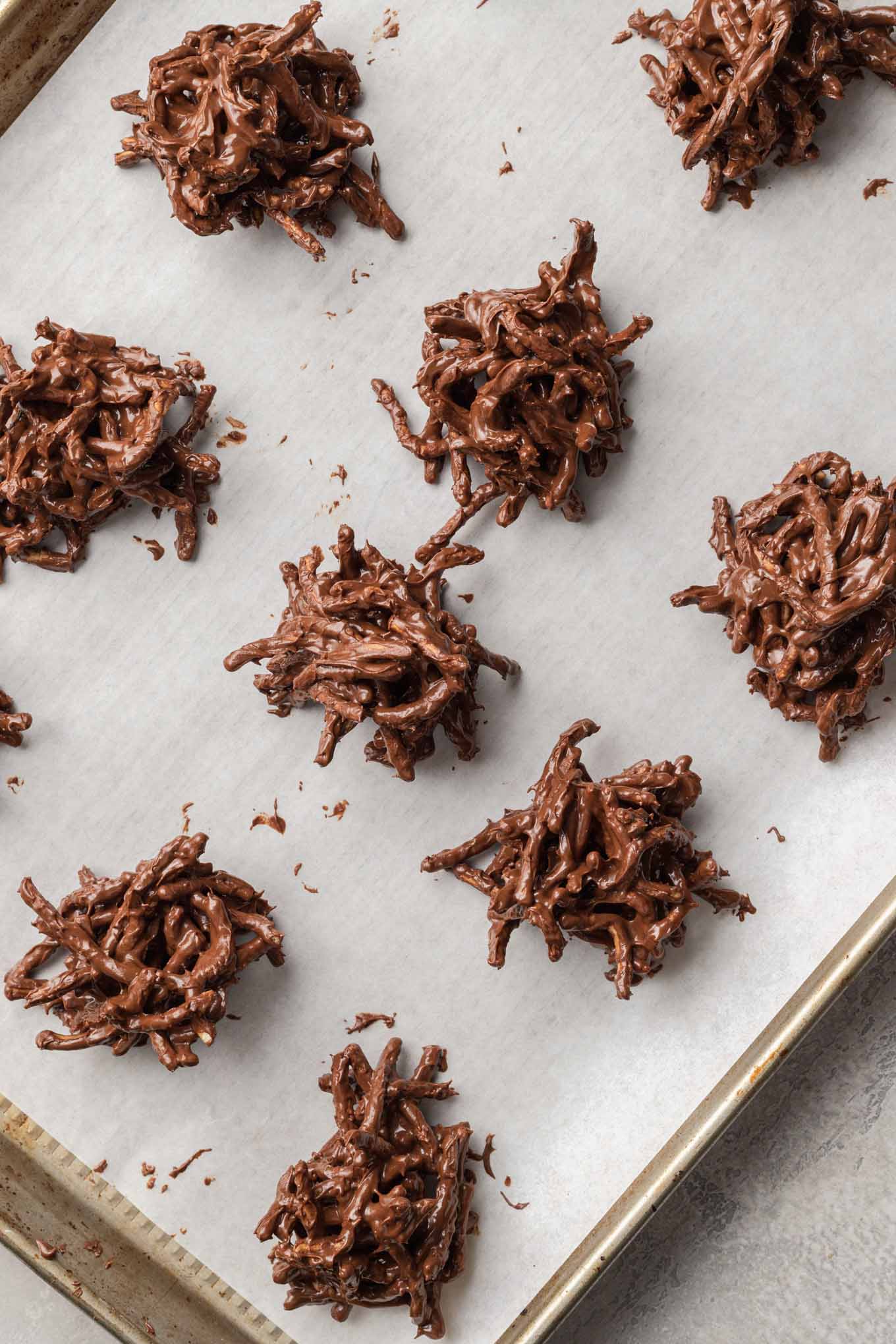 An overhead view of the haystack cookie mixture scooped onto a baking sheet lined with parchment paper.