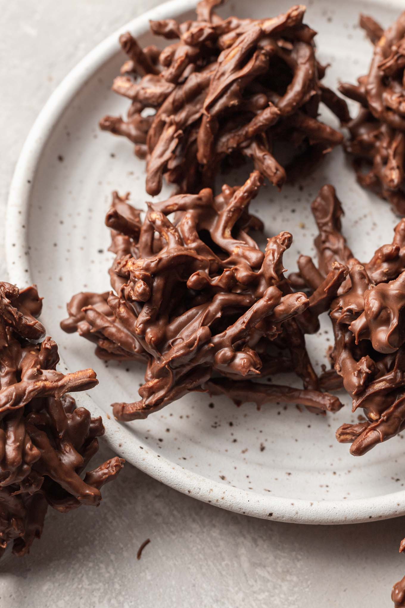 Plain haystack chocolate cookies on a white speckled plate. 