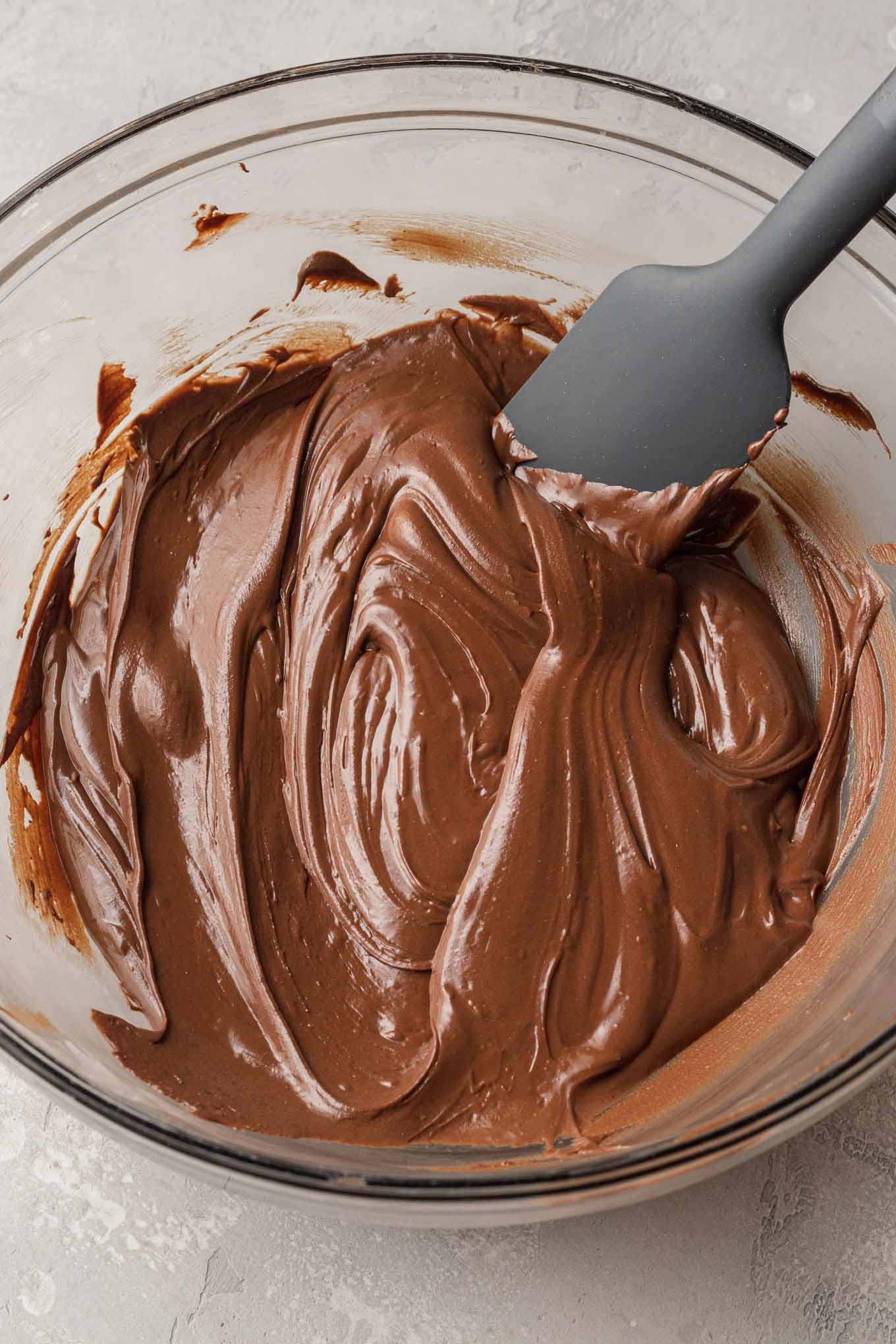 An overhead view of melted chocolate and peanut butter chips in a glass mixing bowl. 