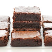 A stack of sliced brownies on parchment paper with more brownies around it.