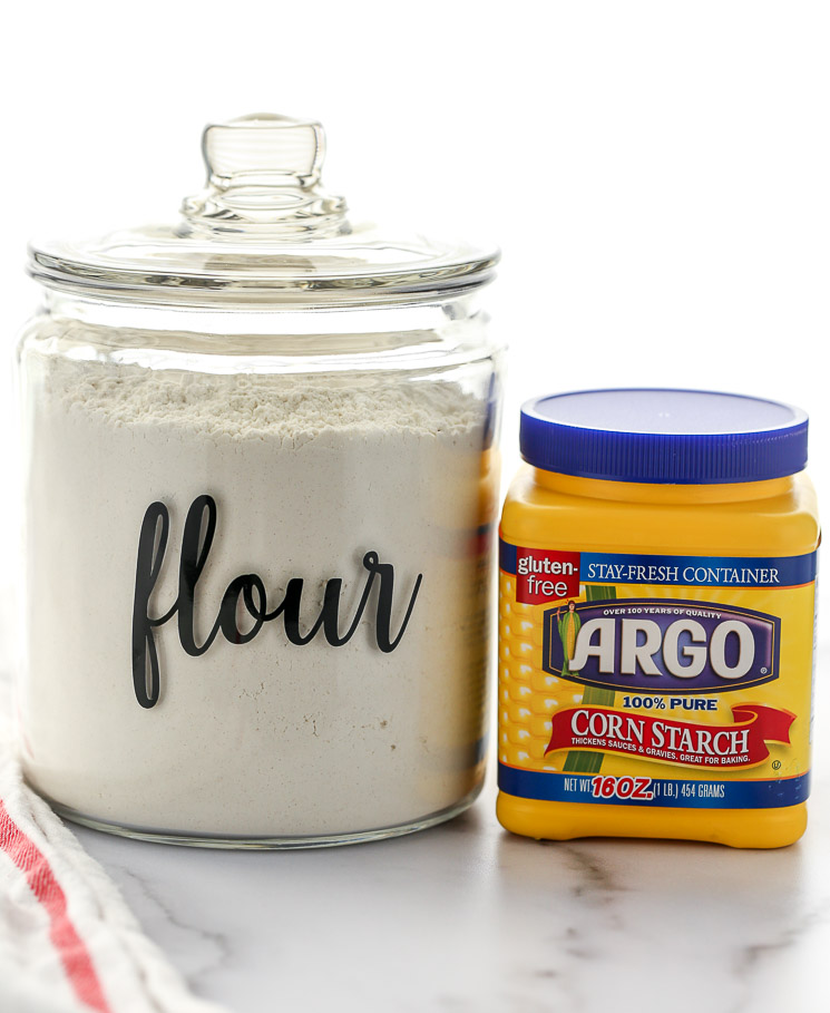 A container of cake flour and cornstarch sitting on top of a marble surface.