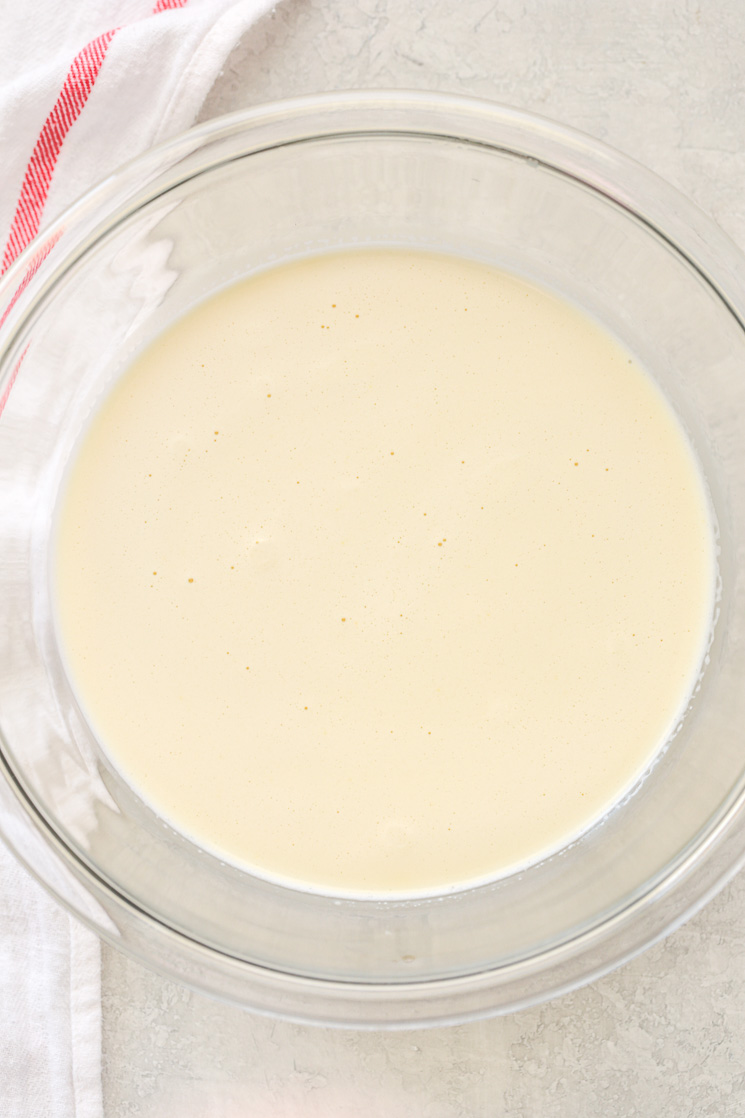 A clear glass bowl filled with the crème brûlée mixture and a white napkin on the side of the bowl.