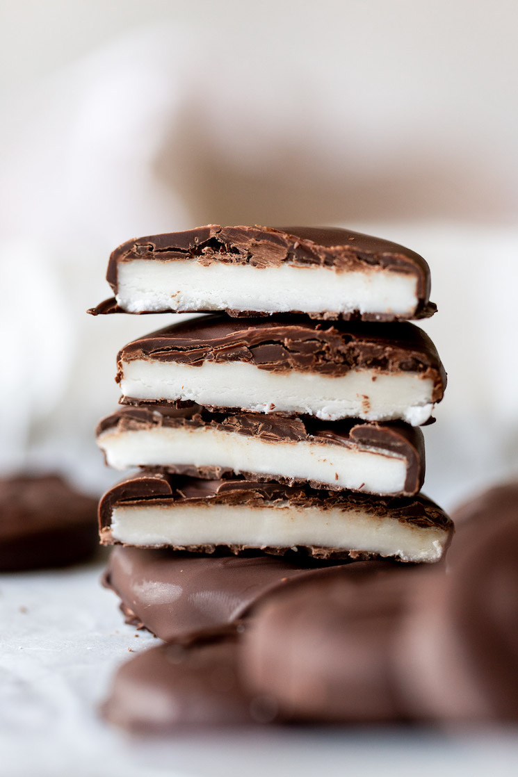 A stack of homemade peppermint patties cut in half to show the different layers.