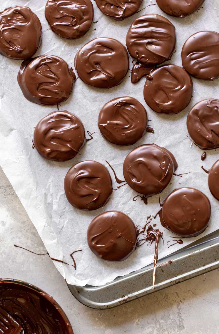 A baking sheet lined with peppermint patties covered in chocolate.