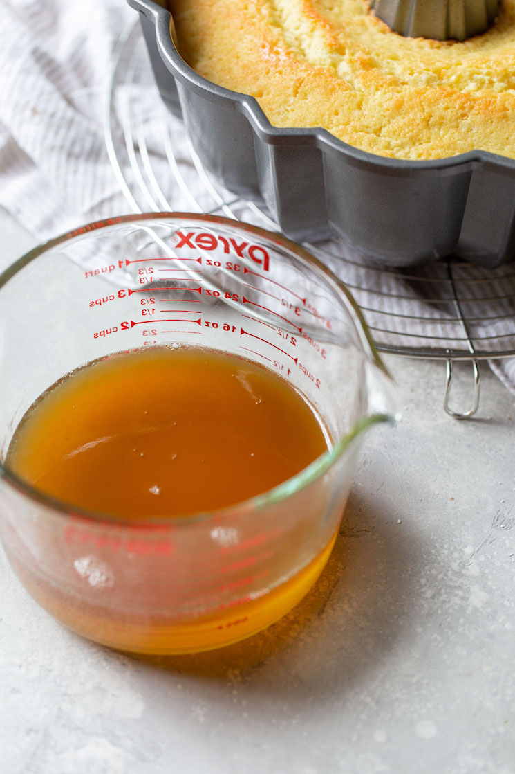 A glass measuring cup holding the rum syrup.