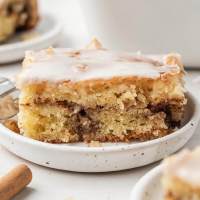 A slice of honey bun cake on a white speckled plate.