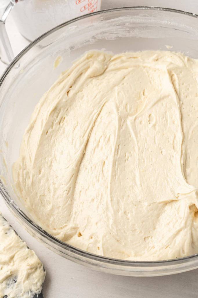 An overhead view of cake batter in a large glass mixing bowl. 