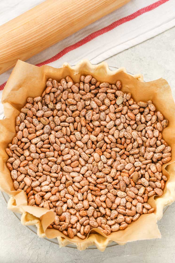 A pie crust that's been topped with parchment paper and dried beans in preparation for blind baking. 