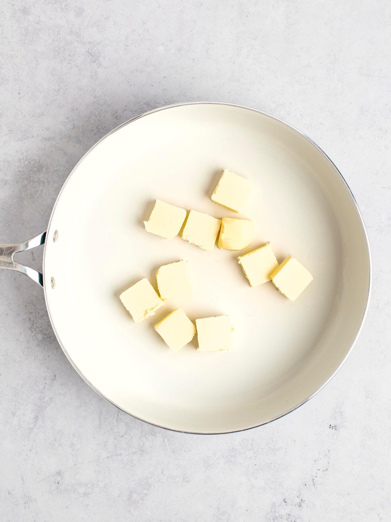 Sliced butter in a white skillet.