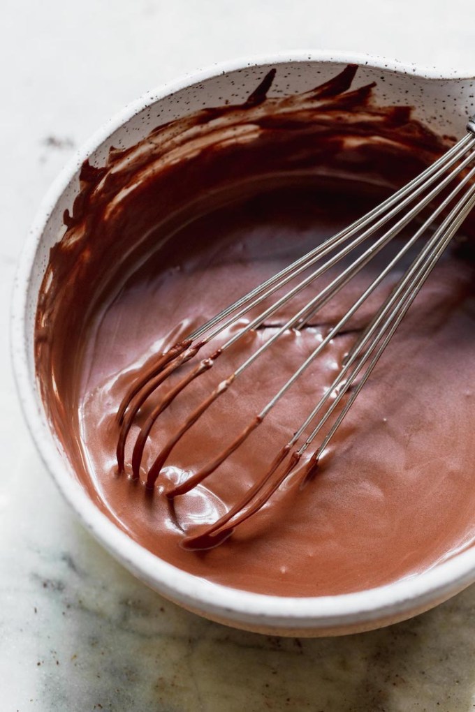 A white mixing bowl holding mixed up chocolate ganache.