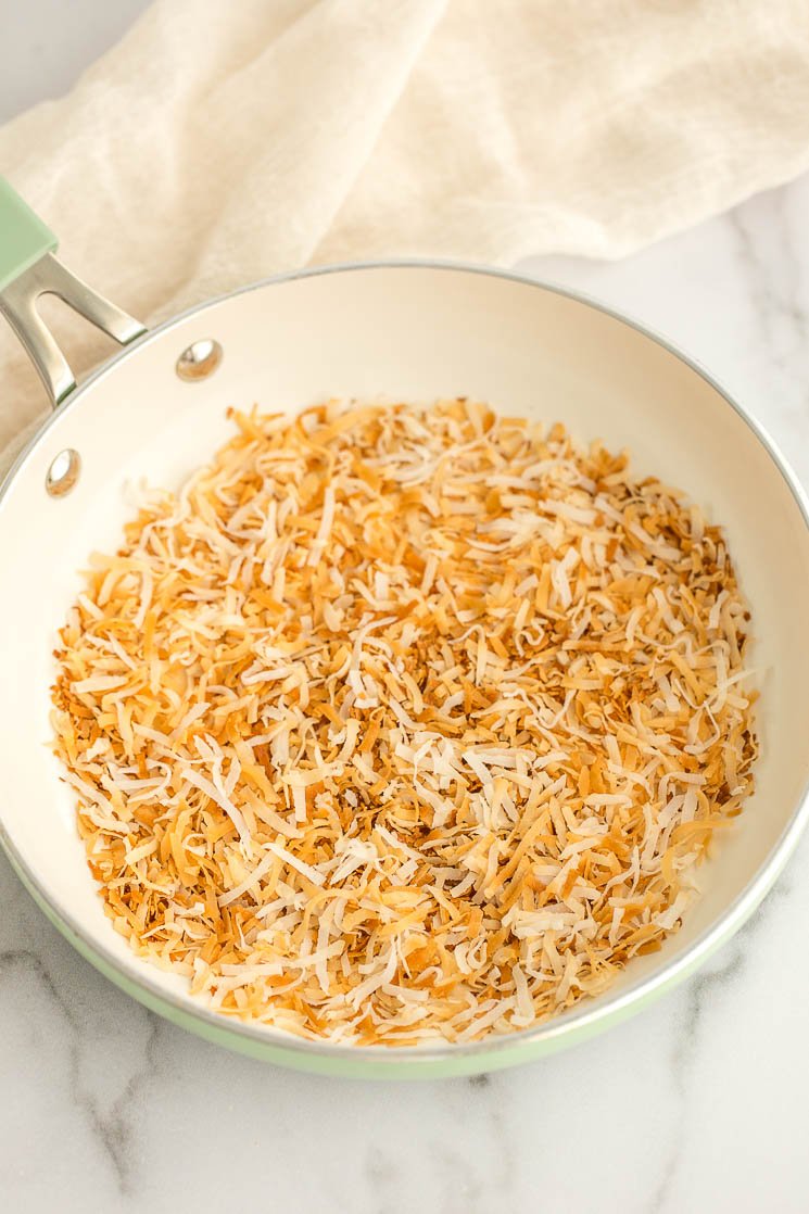 A batch of toasted coconut in a green skillet. 