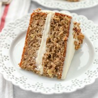 A slice of hummingbird cake on a decorative white plate.