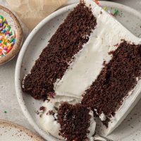 A slice of ice cream cake on a white plate. A fork with a piece of the cake is resting on the side.