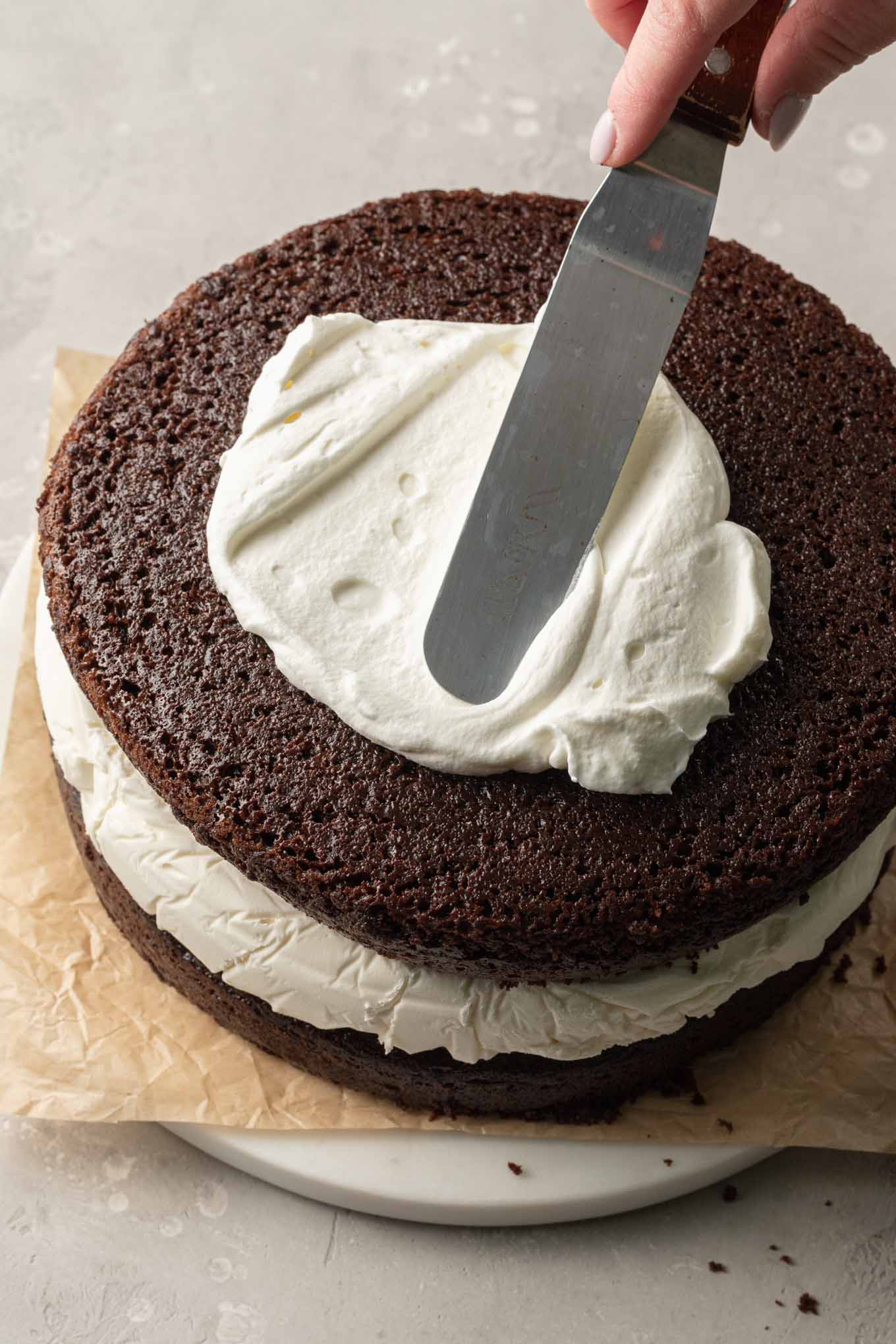 An overhead view showing whipped cream being spread onto the cake.