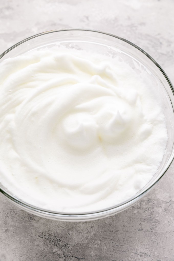 Egg whites beaten to stiff peaks in a glass mixing bowl.