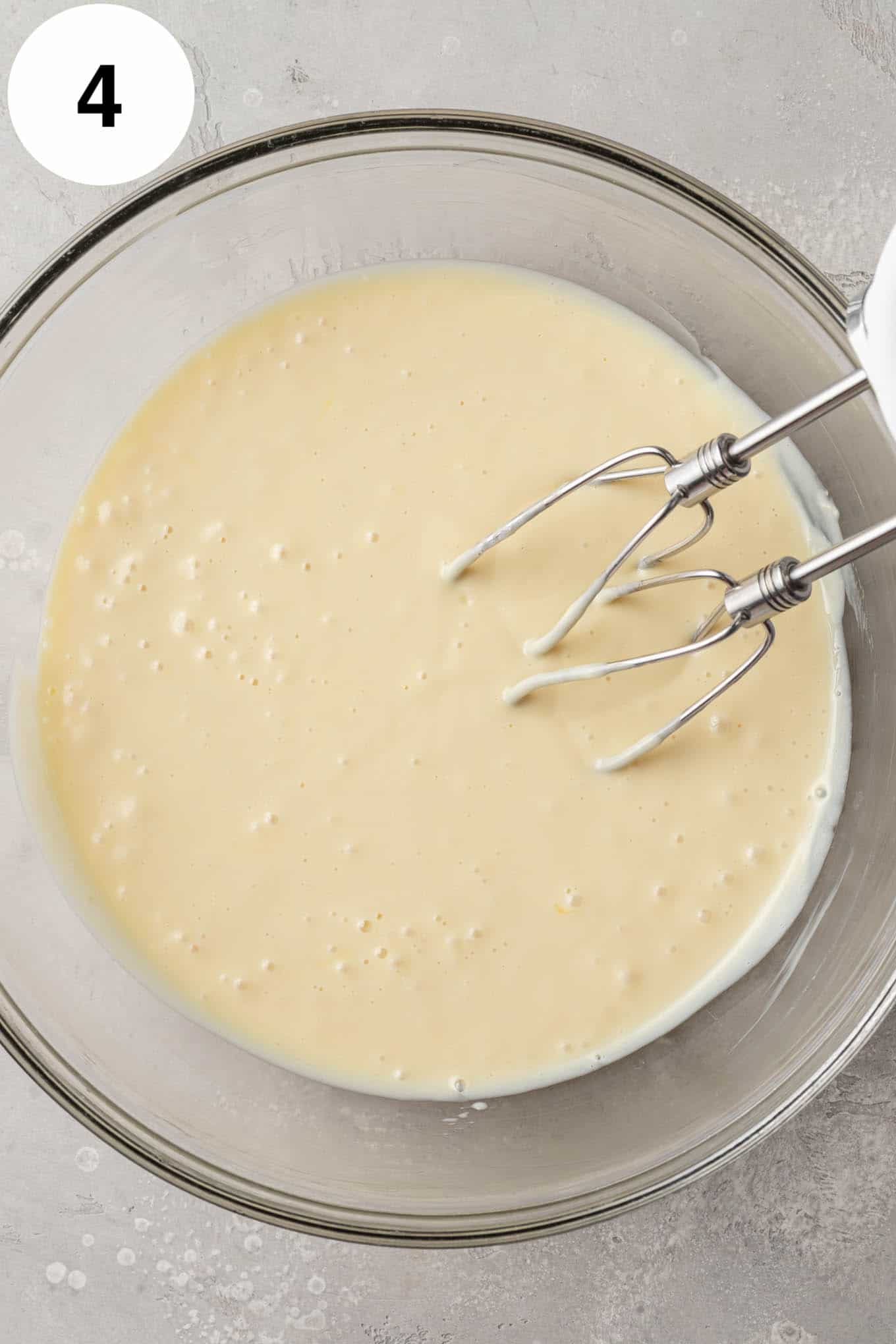 An overhead view of key lime pie filling in a glass mixing bowl. 