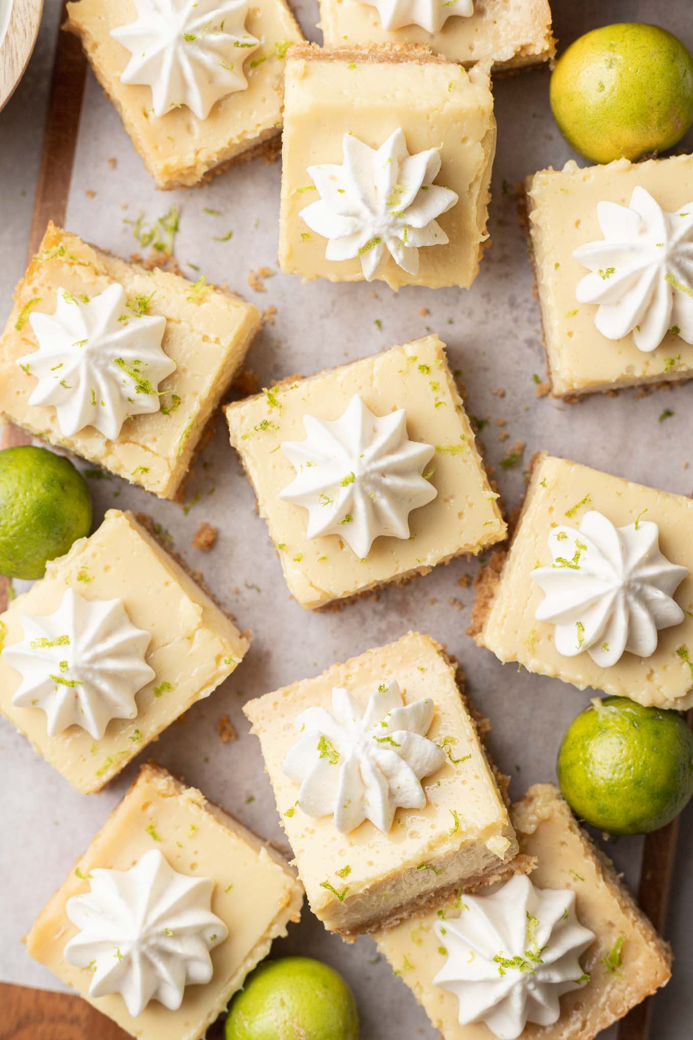 An overhead view of sliced key lime pie bars topped with whipped cream. 