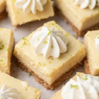 Several sliced key lime pie bars topped with whipped cream.