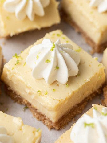 Several sliced key lime pie bars topped with whipped cream.