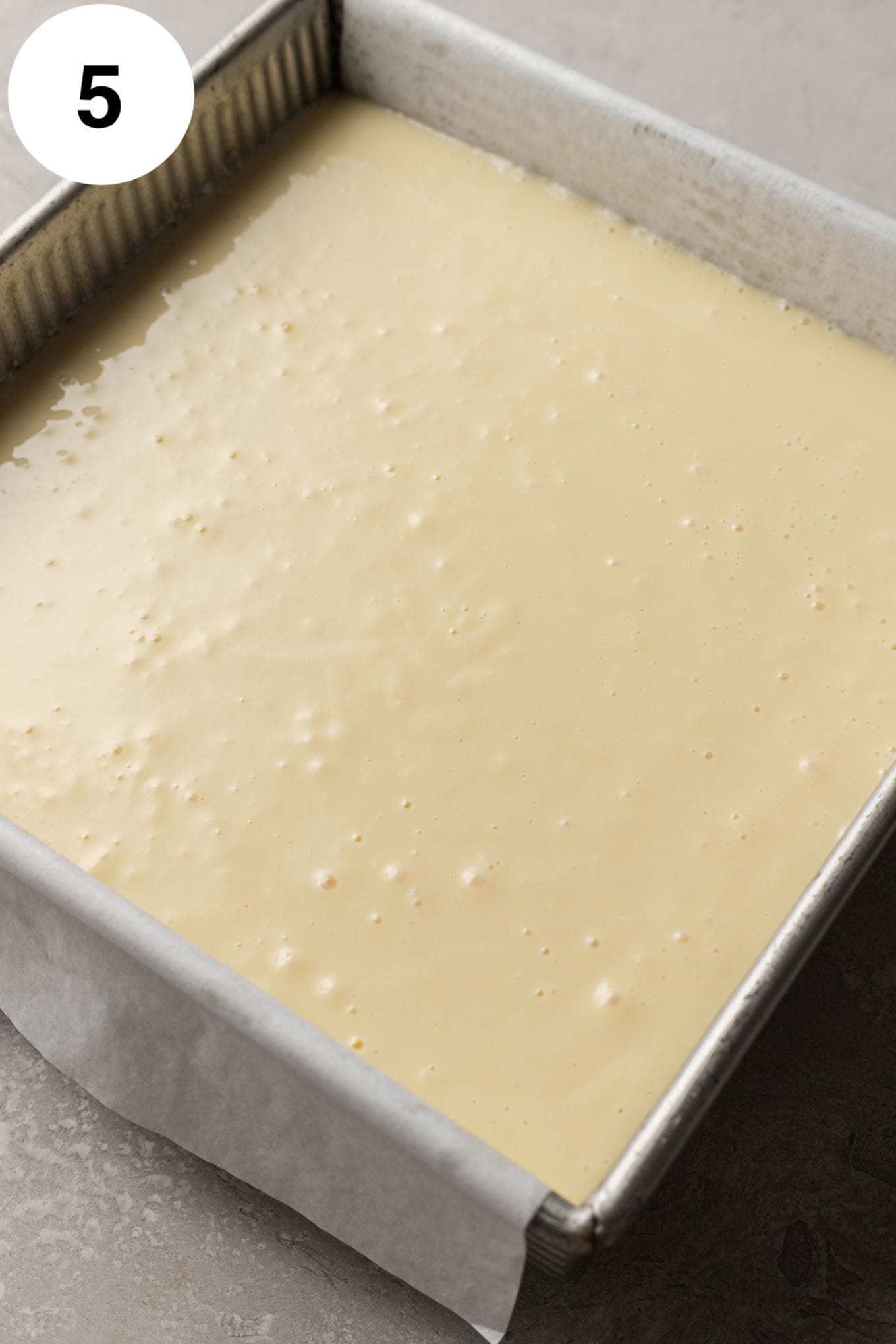 An overhead view of unbaked key lime bars in a square baking dish. 