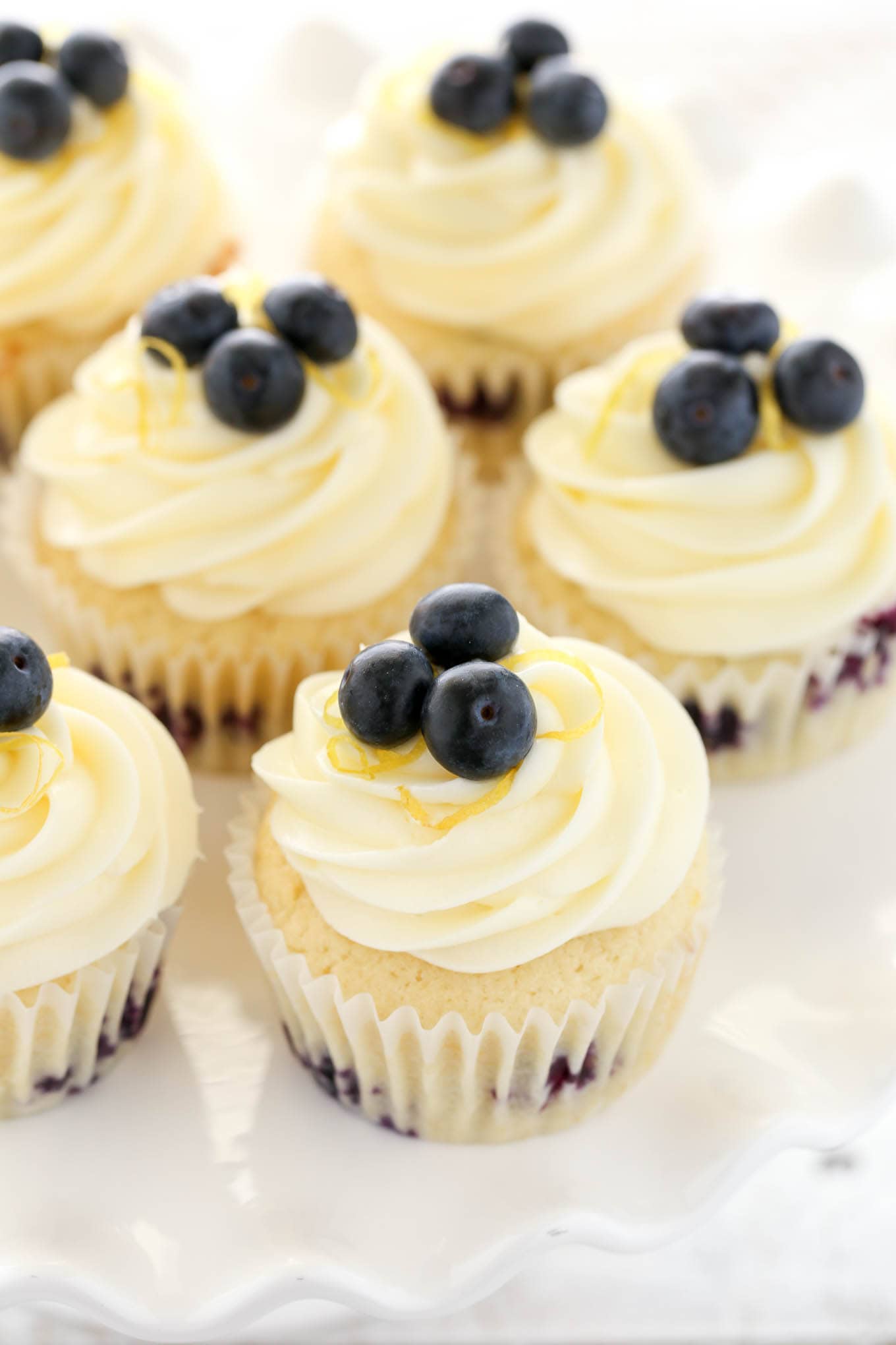 Overhead view of lemon blueberry cupcakes topped with fresh berries and lemon cream cheese frosting. 