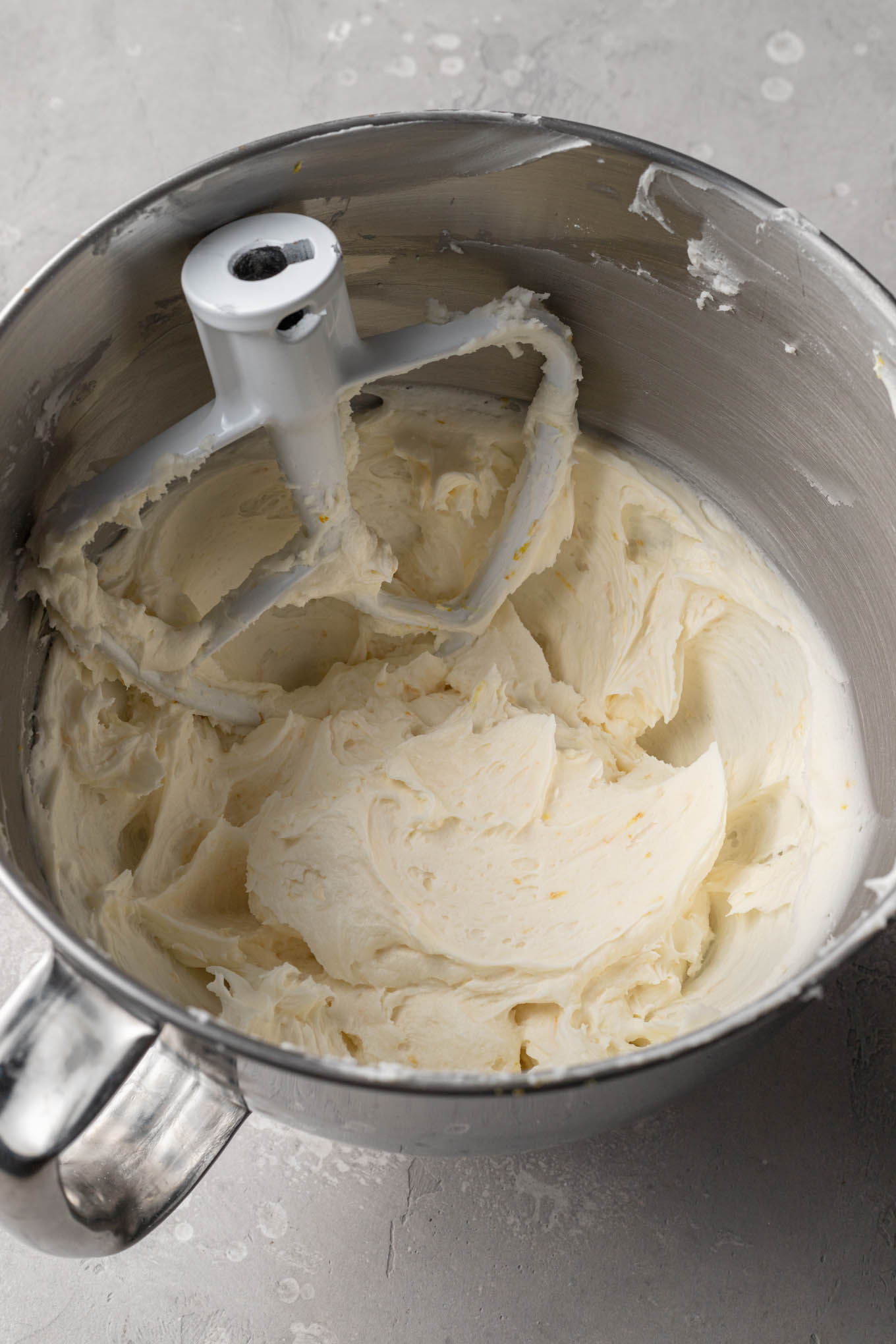 An overhead view of lemon frosting in a mixing bowl. 