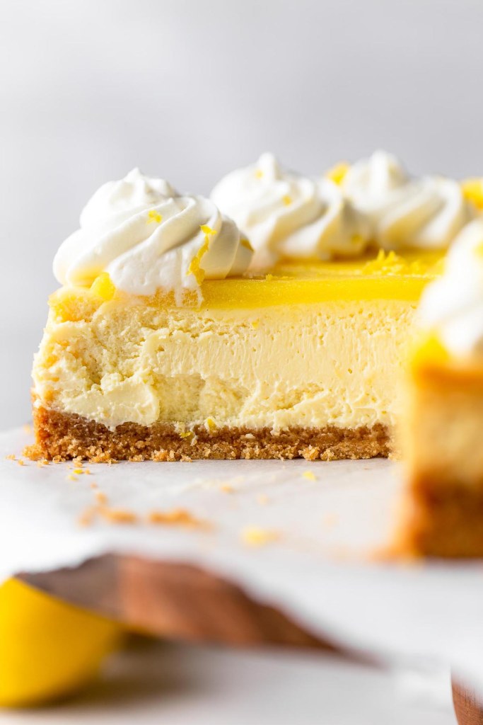 A close-up view of a sliced lemon curd cheesecake, viewed from the side. 