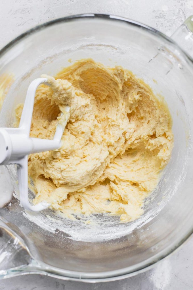 A glass mixing bowl holding cookie batter with the beater still in it.