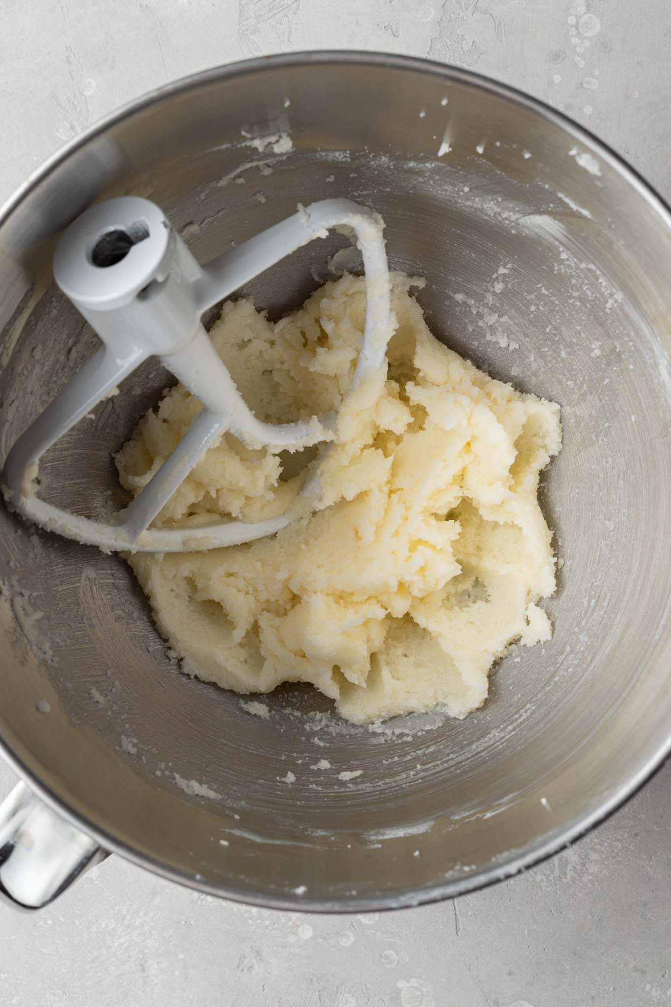 An overhead view of creamed butter and sugar in a mixing bowl. 