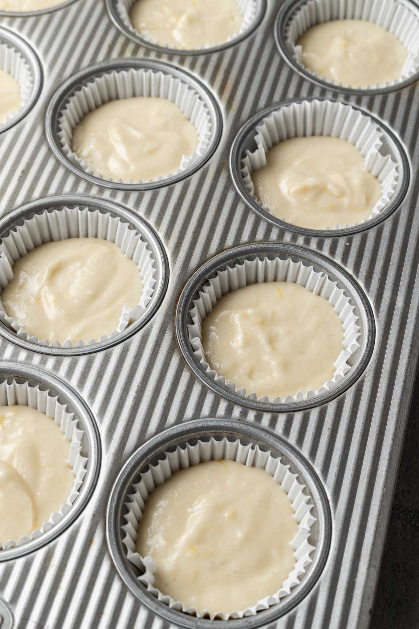 Lemon cupcake batter in lined muffin tins. 