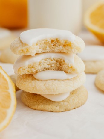 A stack of three lemon meltaway cookies topped with lemon icing. The top cookie is broken in half.