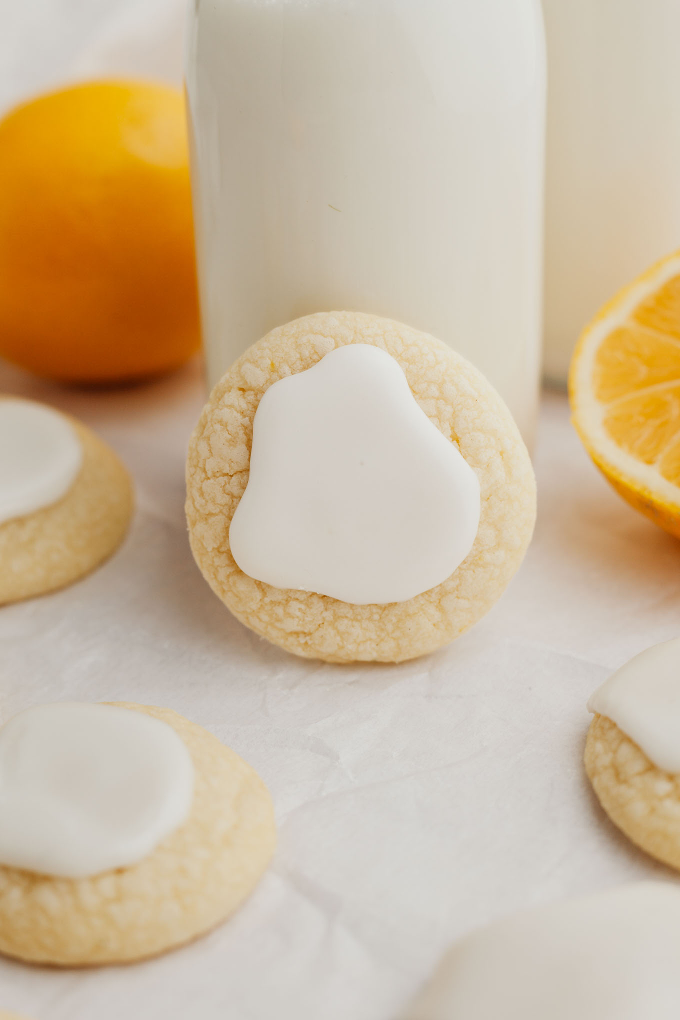 A lemon meltaway cookie propped up on a small jug of milk.