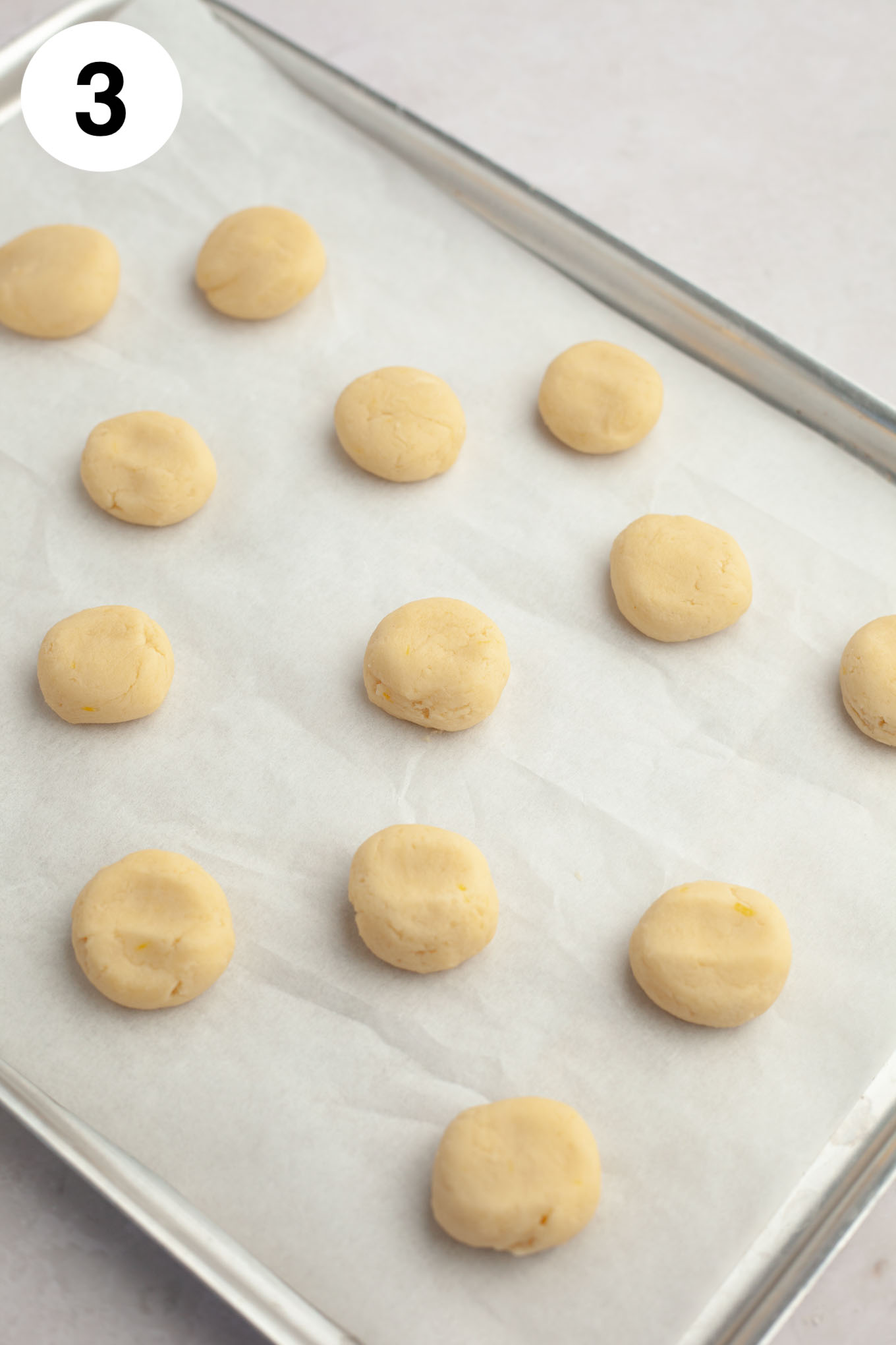 Unbaked lemon meltaway cookie dough on a parchment paper-lined baking sheet. 