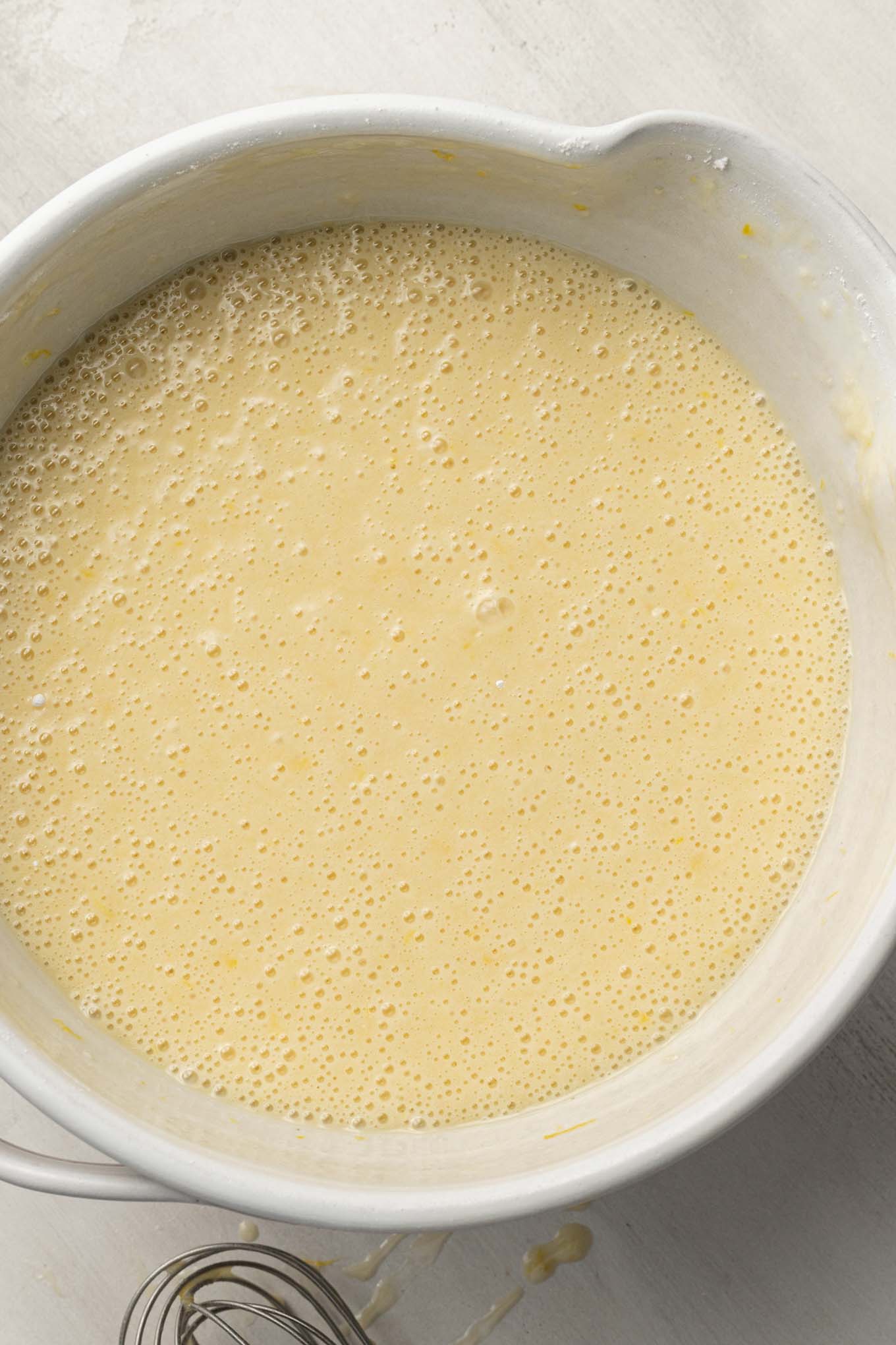 Lemon olive oil cake batter in a white ceramic mixing bowl.