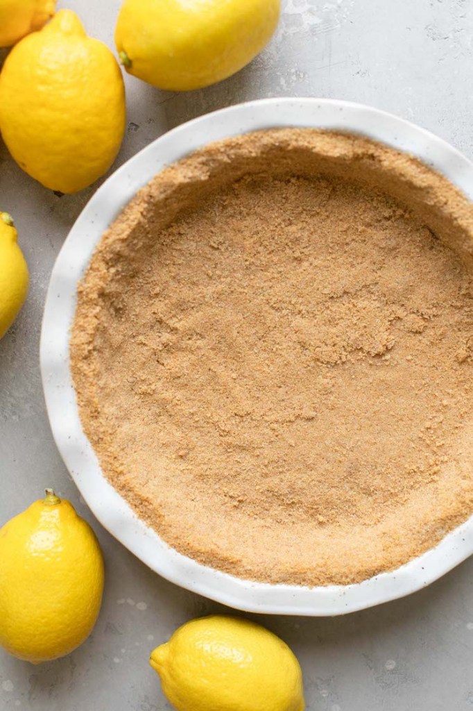 A white baking dish holding a graham cracker crust ready to be filled with the pie filling.