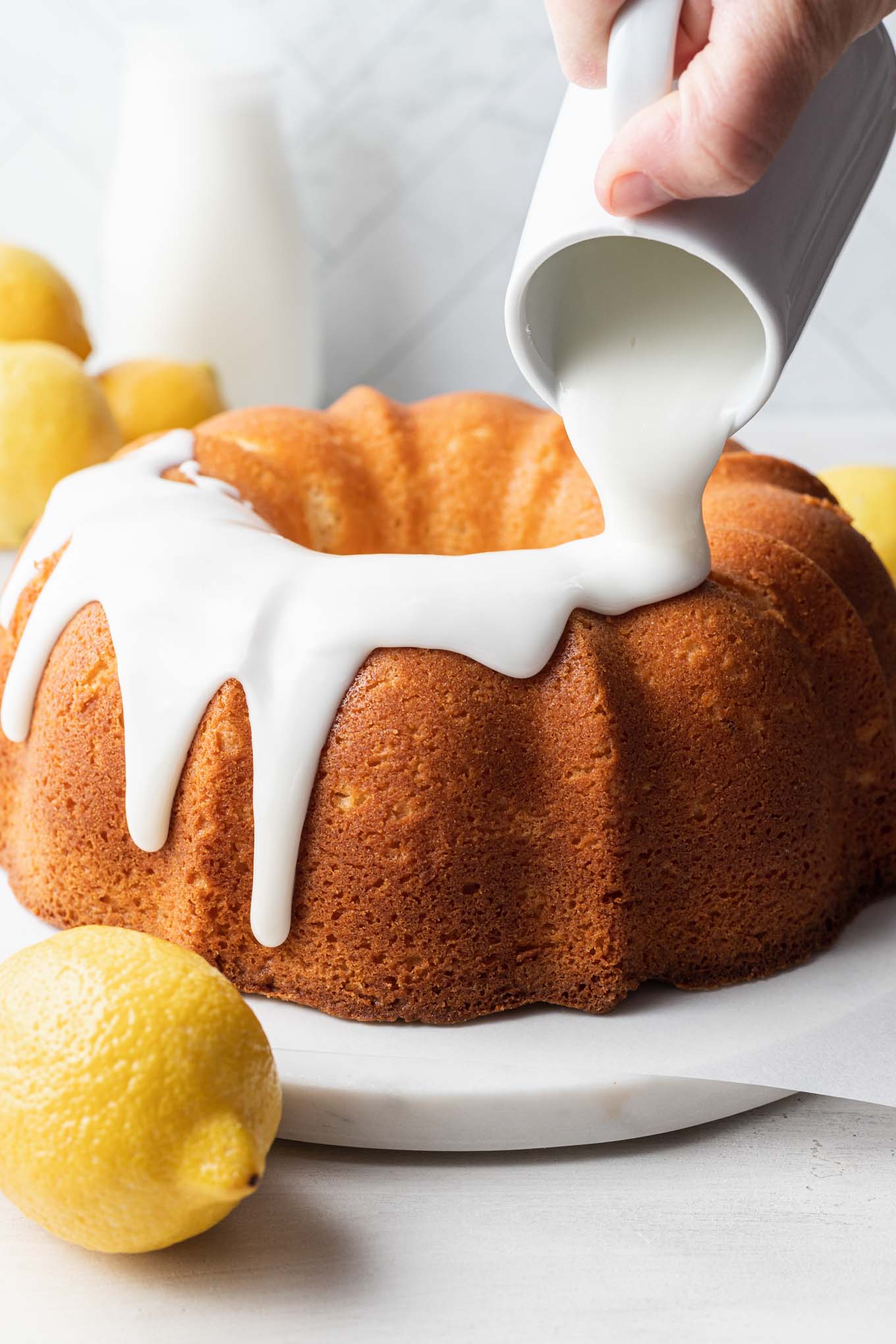 Lemon glaze being poured over a pound cake. 