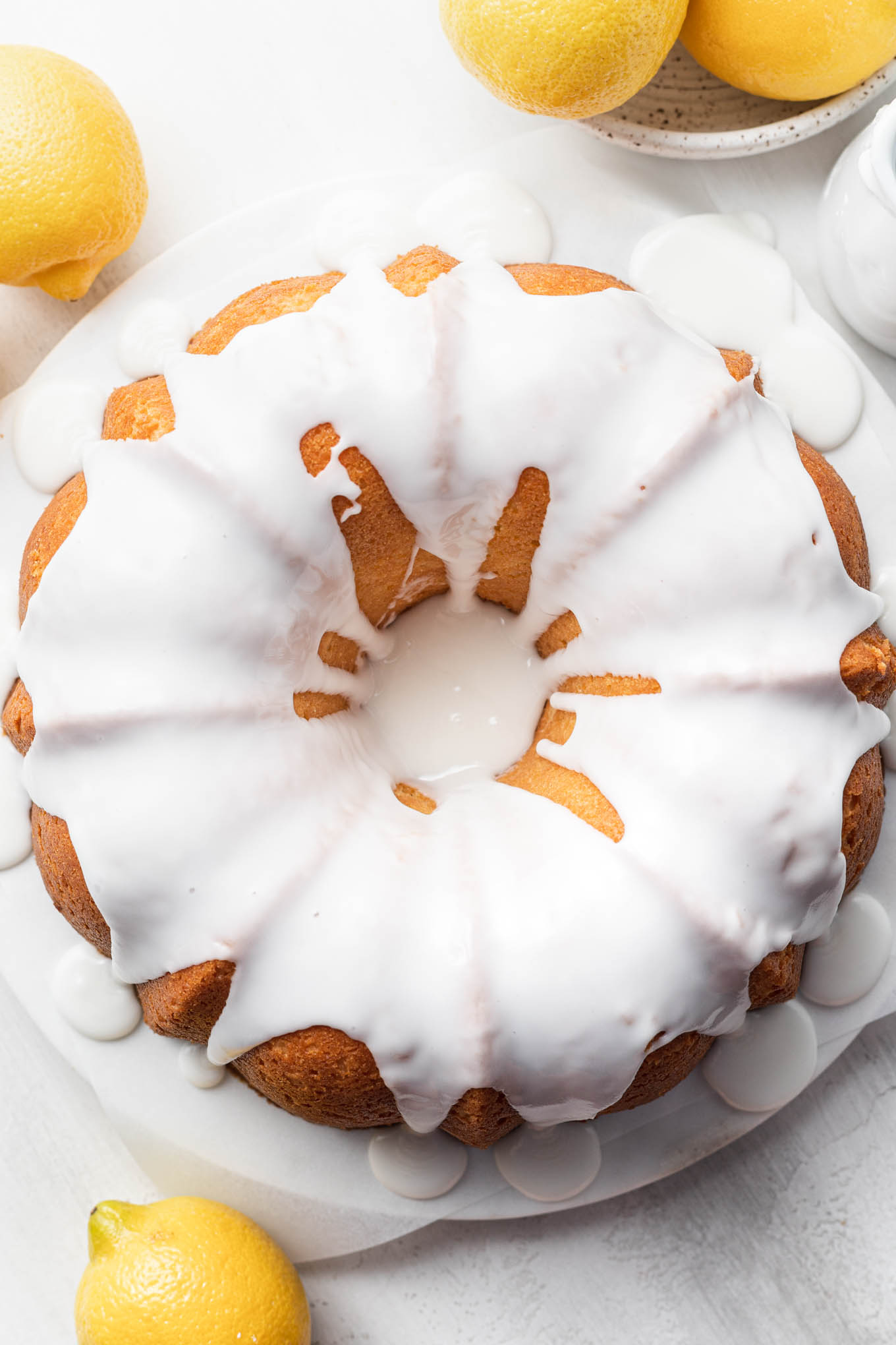 An overhead view of a lemon pound cake topped with glaze, surrounded by lemons. 