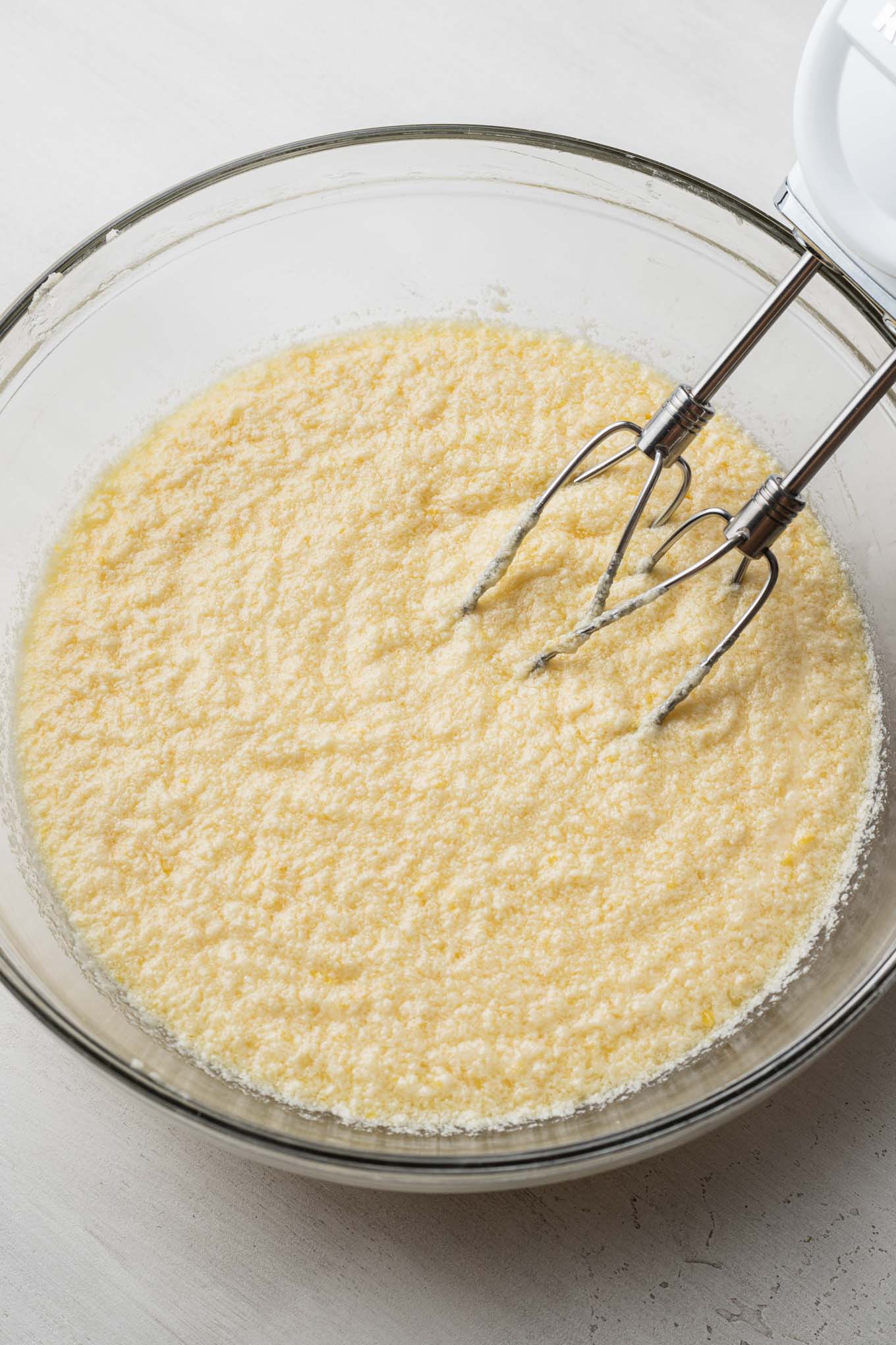 Creamed butter and sugar in a glass mixing bowl with an electric handheld mixer.