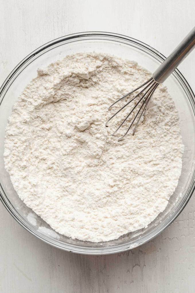 An overhead view of a bowl of dry ingredients, with a whisk.