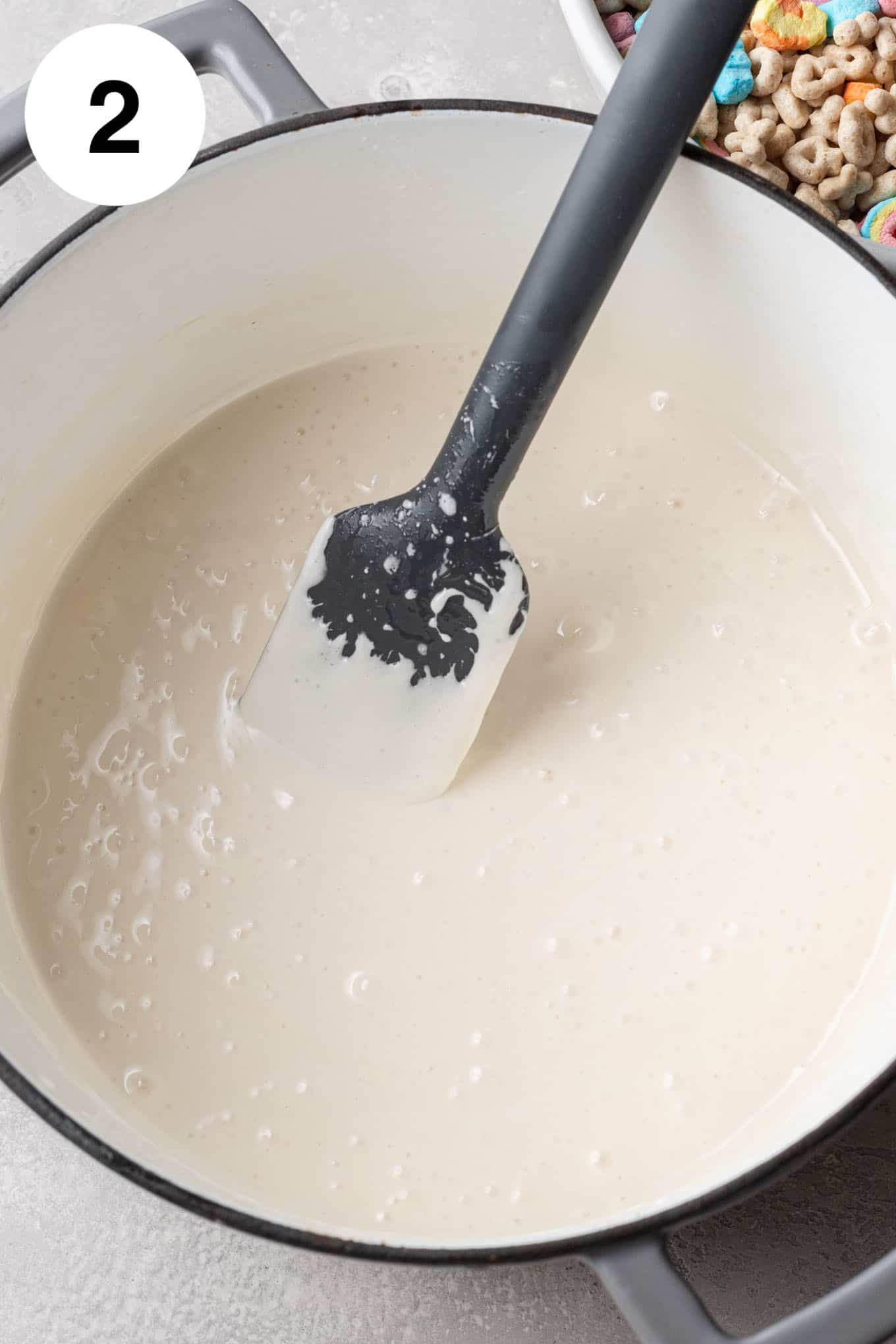 An overhead view of melted butter and marshmallows in a large saucepan. 