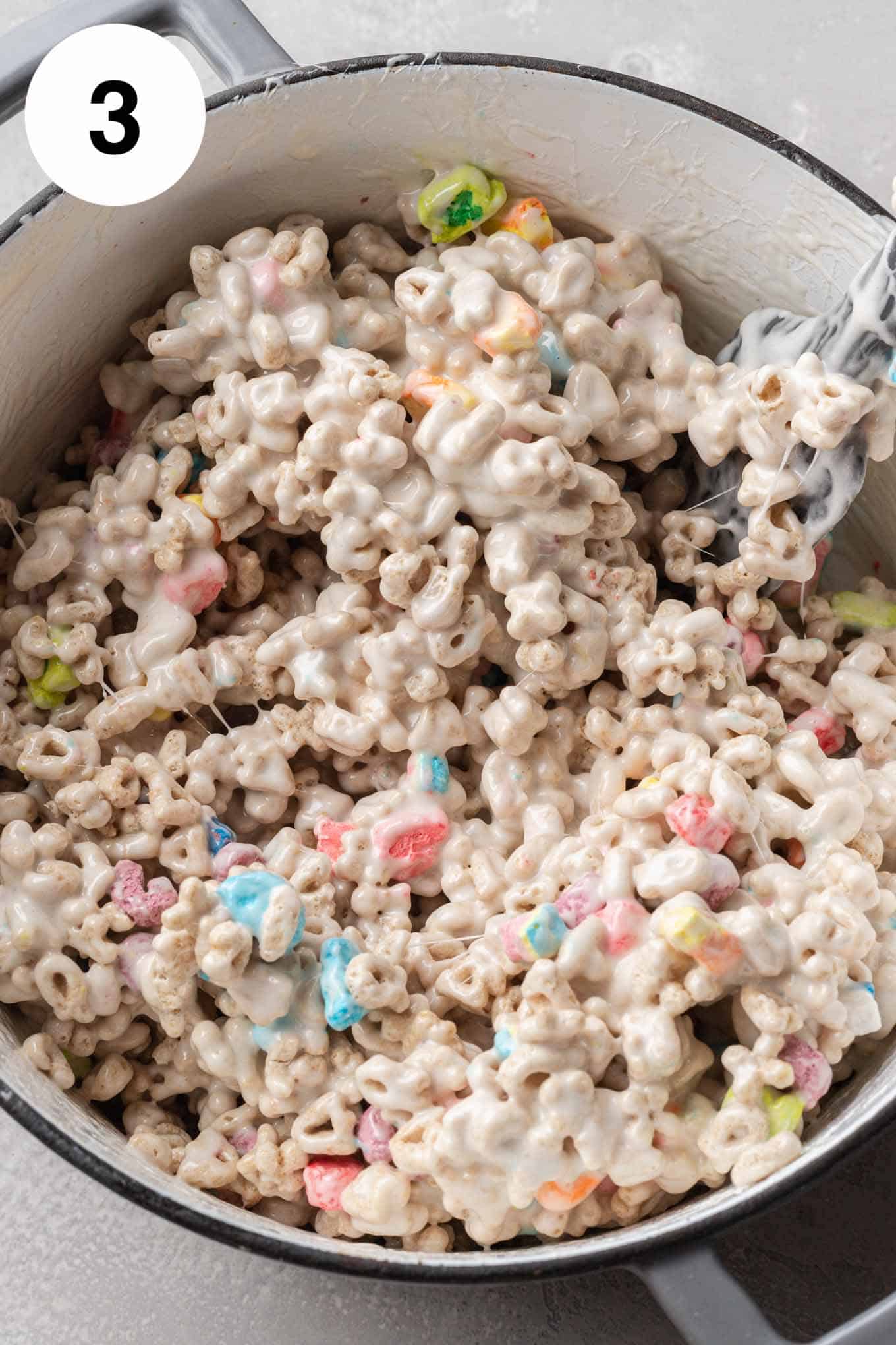 An overhead view of Lucky charms coated in marshmallows, in a large saucepan. 